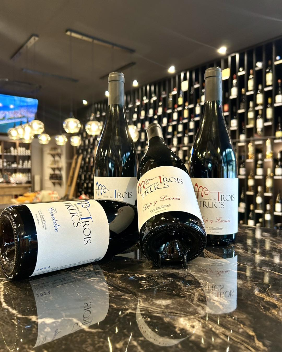 Les bouteilles du domaine posées sur un comptoir de marbre, chez un caviste